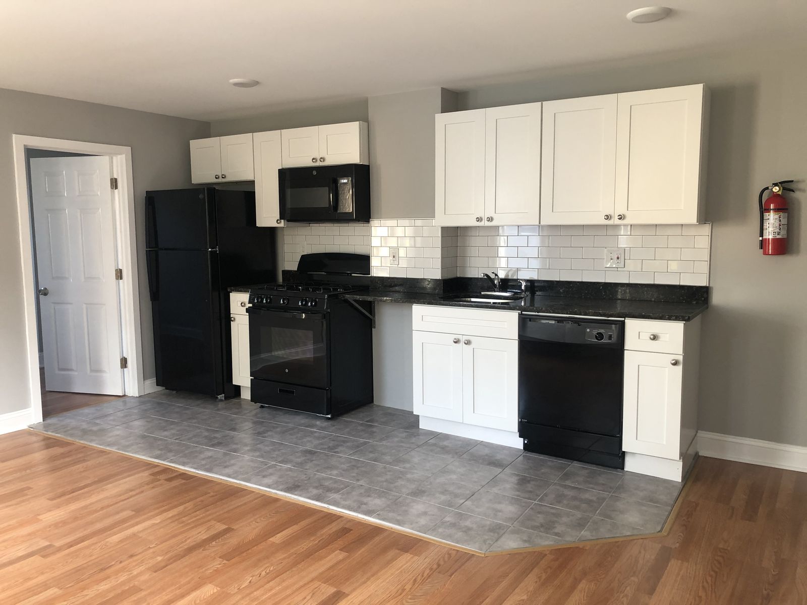 Finished rental kitchen with white cabinets and dark countertops